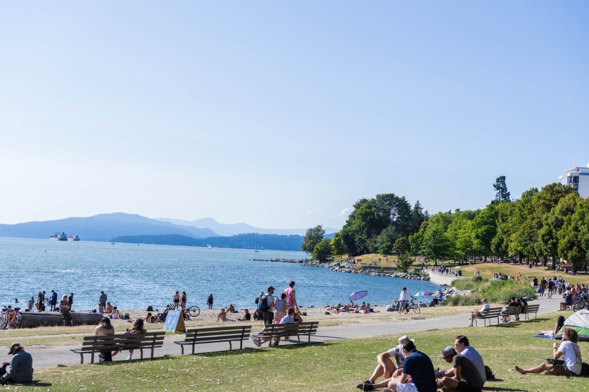 People sitting around in the park at English Bay in Vancouver