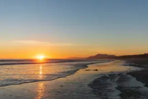 The sunset over the waves and sand of Long Beach in Tofino