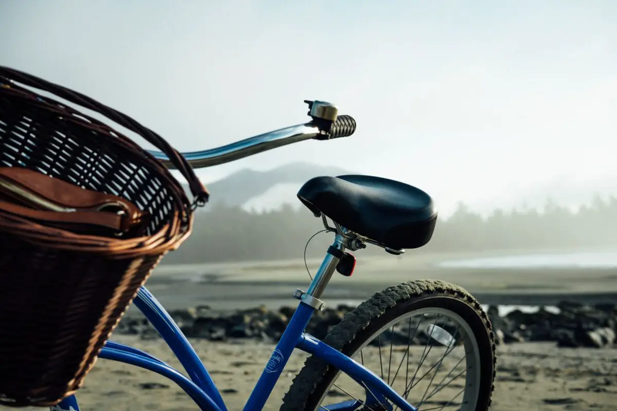A blue bike with a basket with Chesterman Beach in the background, in Tofino 