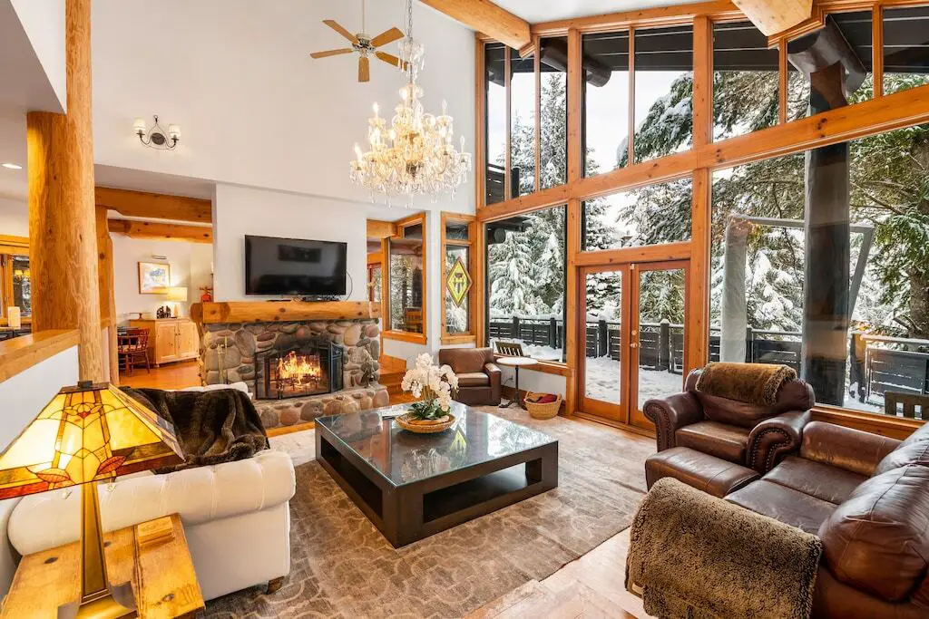 The living room at the Blueberry Hill Chalet in Whistler BC, with a crackling fire and a snowy outdoors