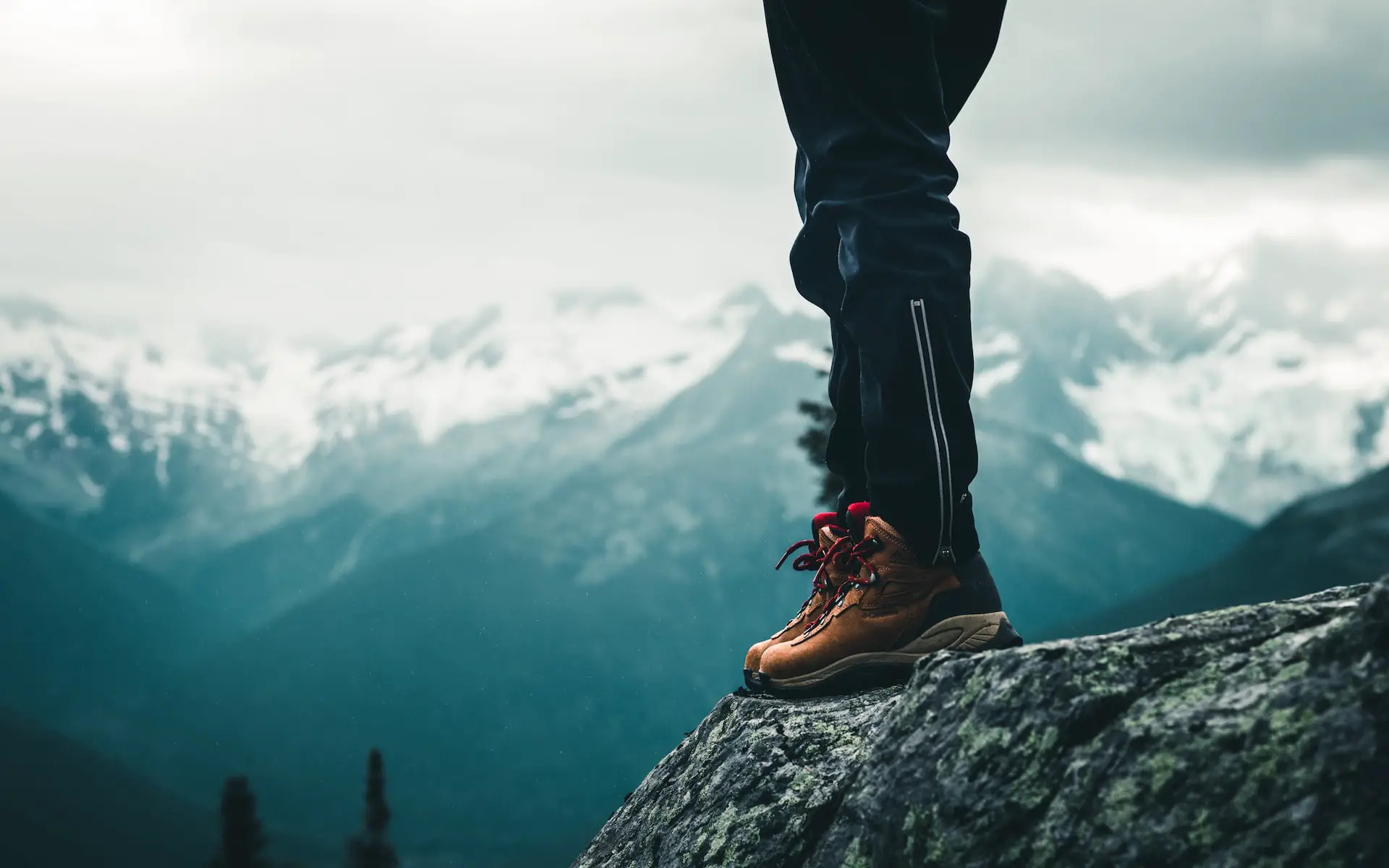 Someone wearing hiking boots with a background of mountains