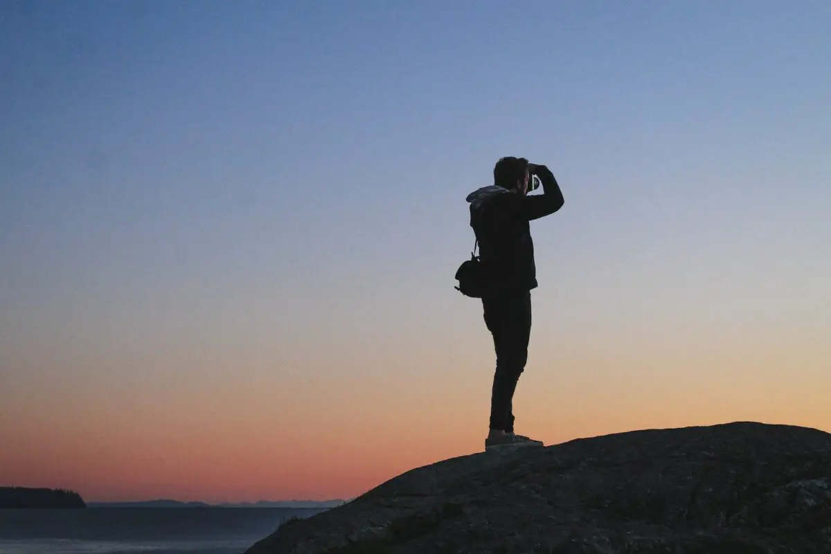 A person taking a photograph at Whytecliff Park in North Vancouver as the sun sets