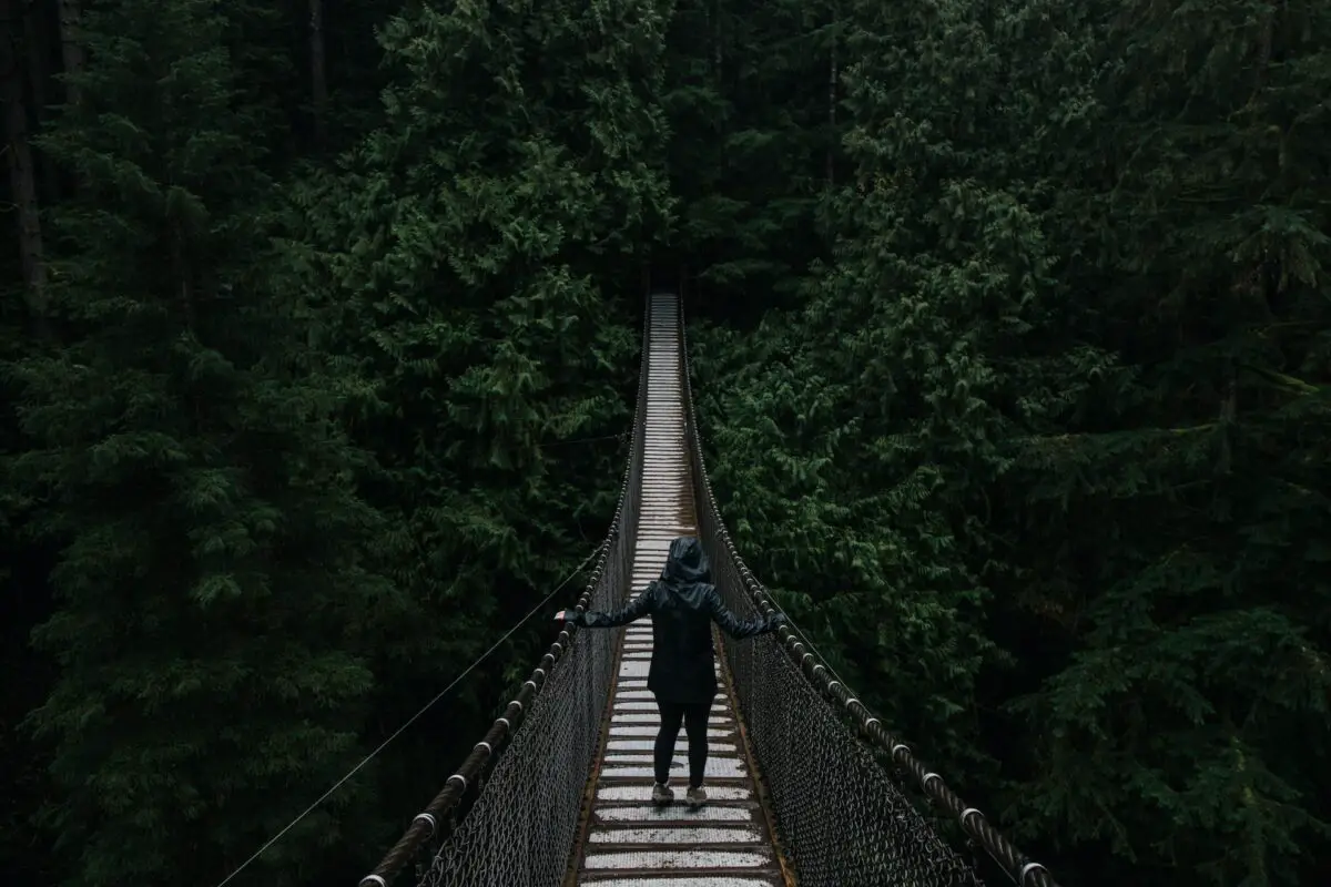 A person in a raincoat standing on the suspension bridge in Lynn Canyon Park, Vancouver