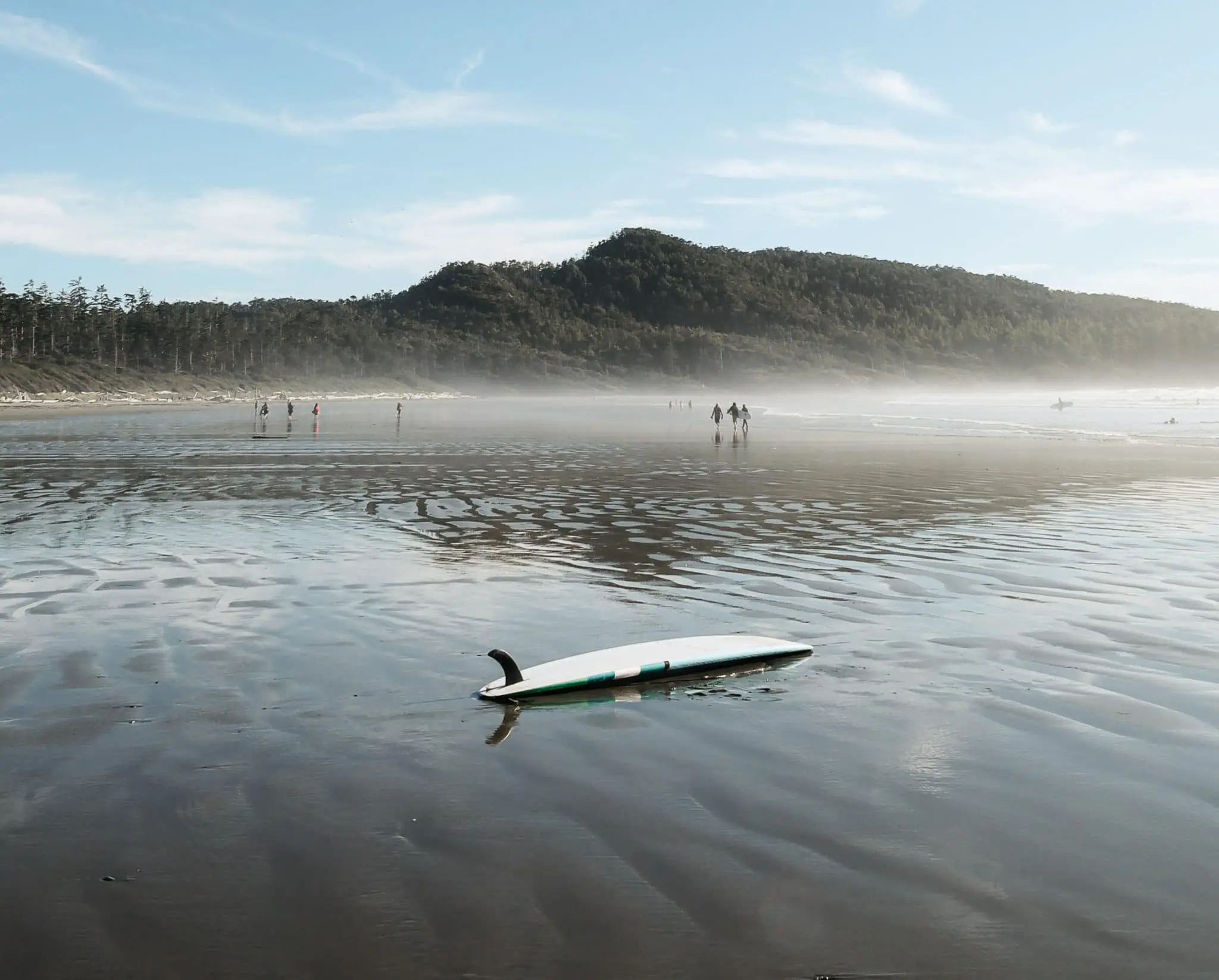 A surfboard laying on a beach in Tofino
