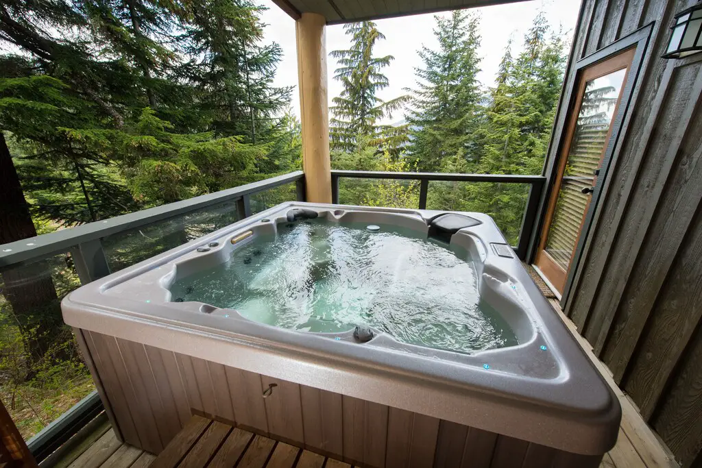 The hot tub surrounded by views of trees and mountains at Taluswood Ridge Townhome in Whistler, BC