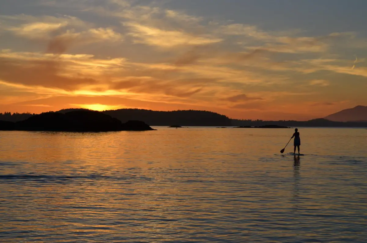 Paddleboarding towards the sunset above the hills in Tofino