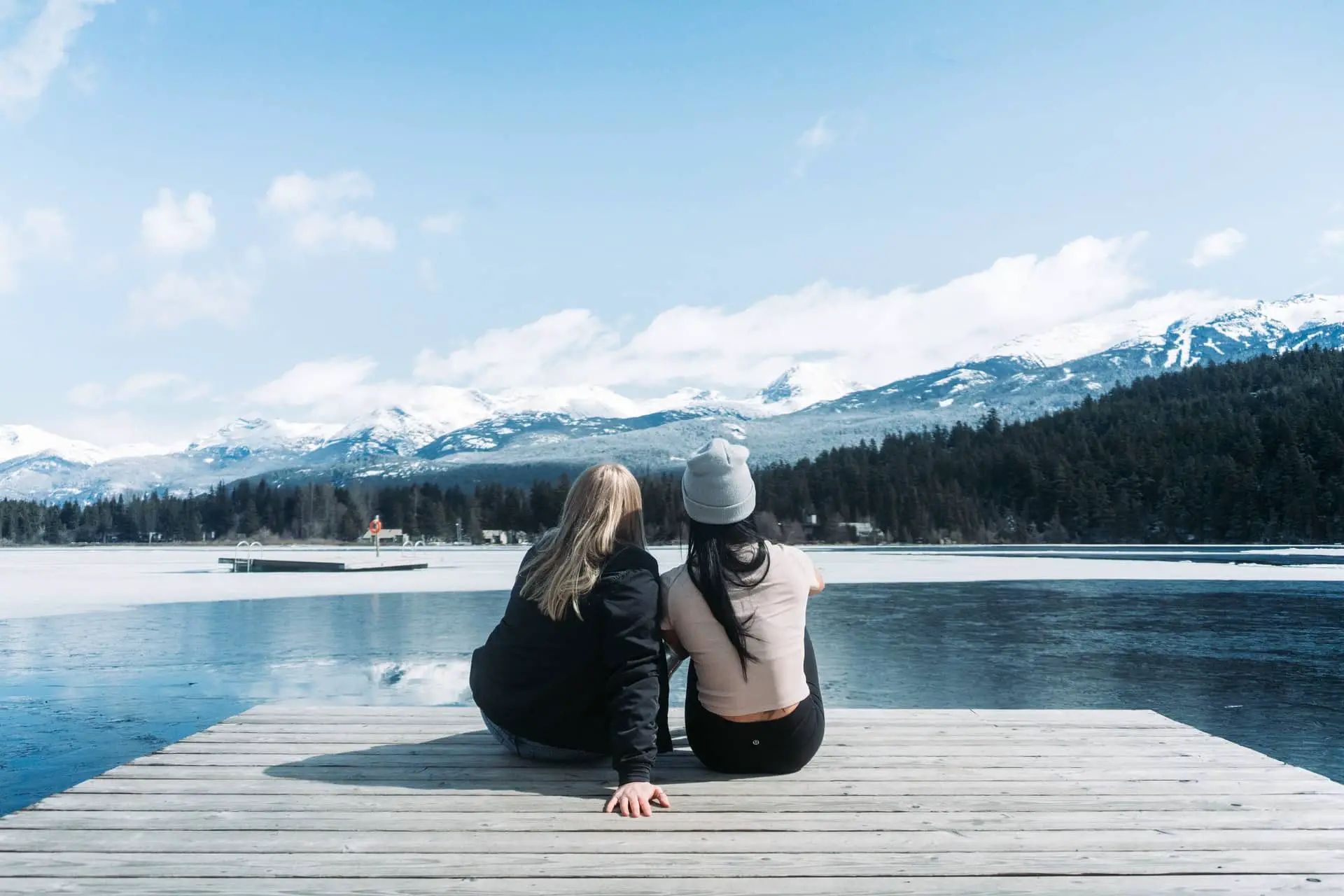 A couple sitting on the boardwalk at the lake in Whistler, BC