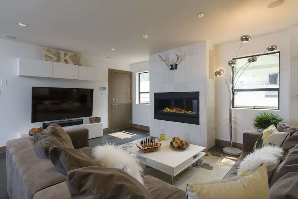 The living room with a couch, TV, and fireplace in the White Gold Chalet in Whistler, BC